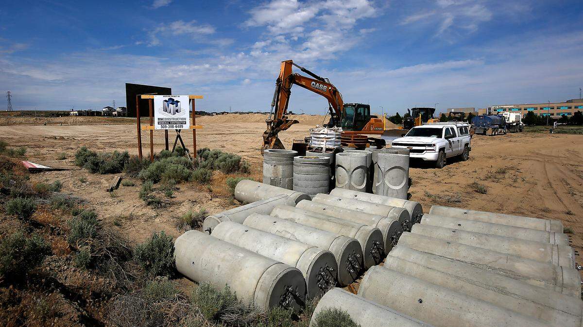 Building supplies and heavy equipment are staged in a field for construction of a new car dealership in Kennewick.