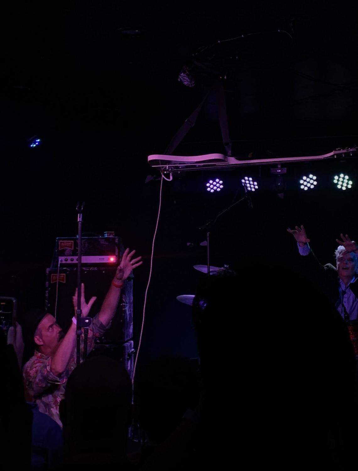 Krist Novoselic hangs his bass up on stage at Ray’s Golden Lion and puts his hands up, alongside Mark Pickerel.