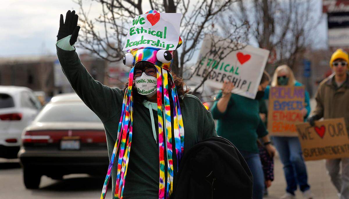 Tracy Sutton, a Richland School District para-educator, waves to passing motorists Thursday morning along George Washington Way near John Dam Plaza in Richland during a rally held by the Community for an Ethical School Board. Several hundred people participated.