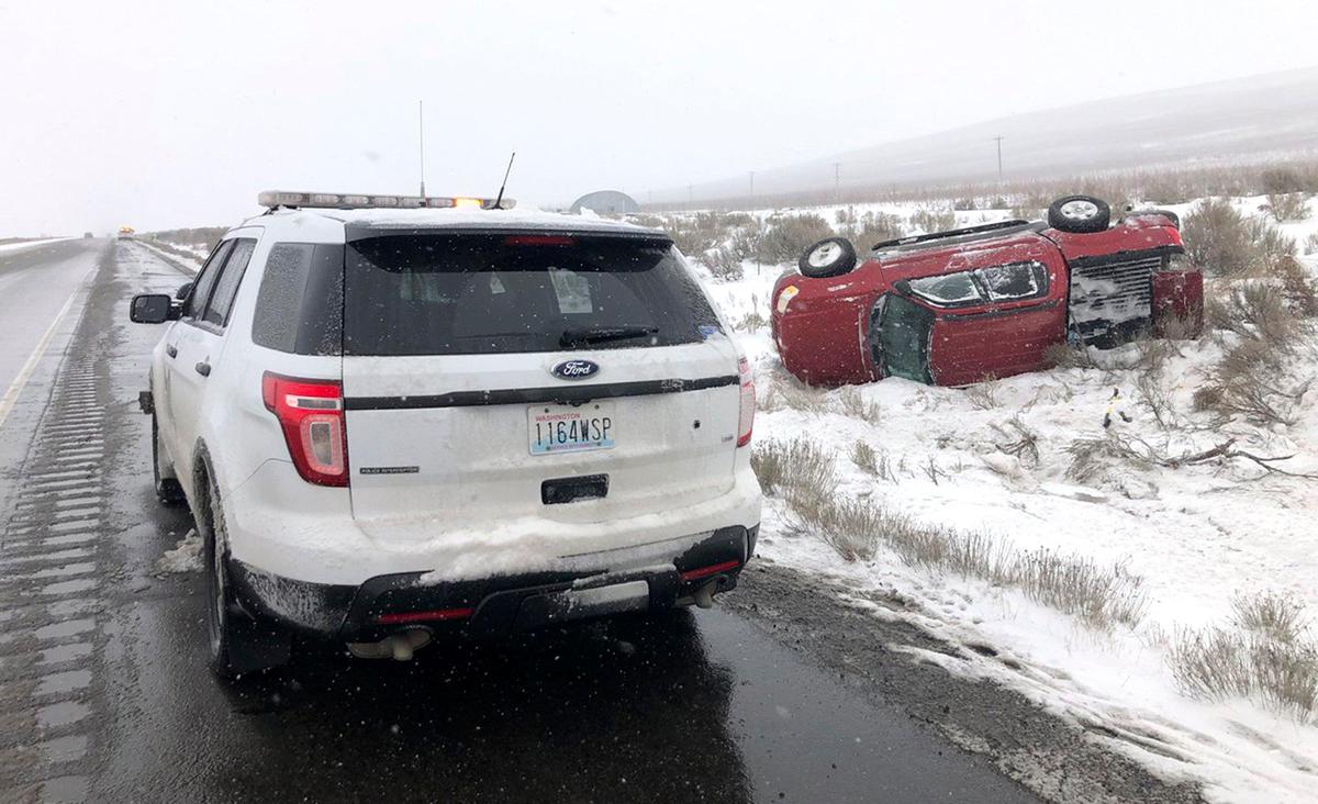 A trooper from the Washington State Patrol investigates a rollover wreck Monday afternoon on Interstate 82 near Benton City. Troopers were called to multiple collisions along the highway between Benton City and Oregon during the winter storm.
