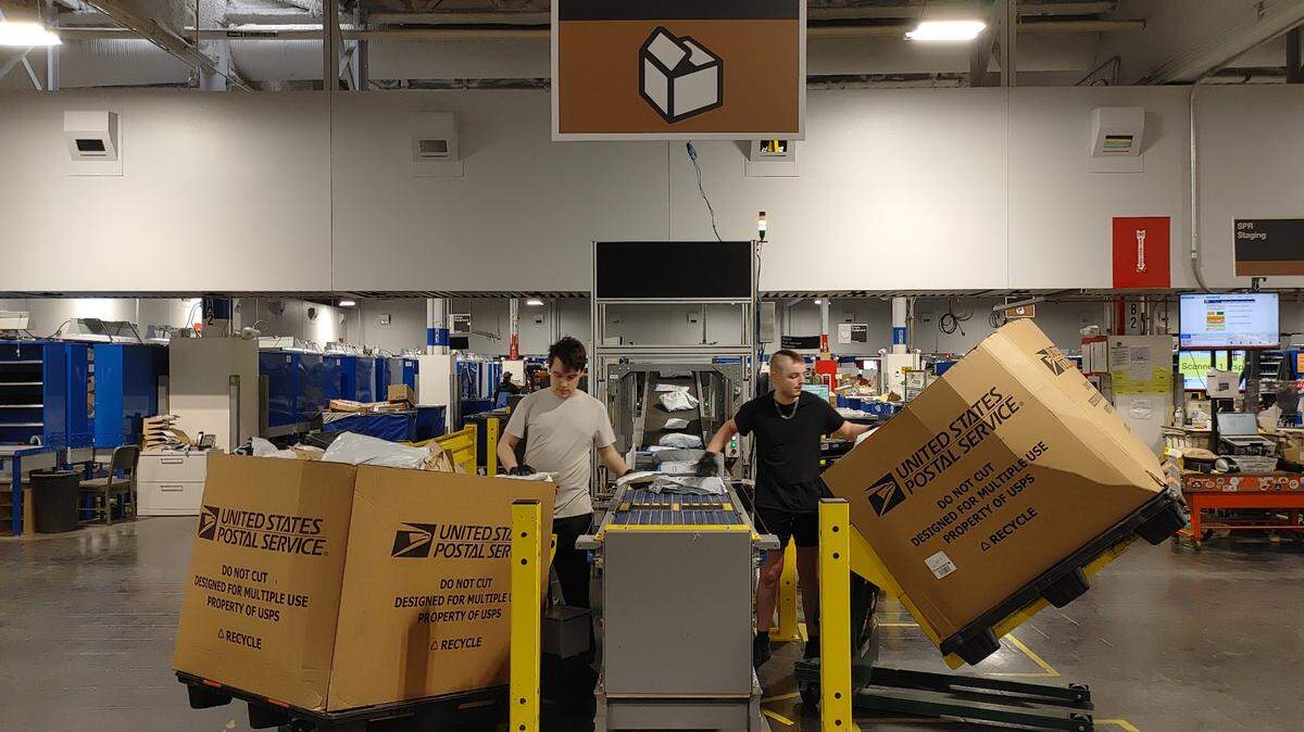 U.S. Postal Service workers at the Pasco sorting and delivery center load packages into a new processing system that scans delivery codes. The equipment can handle 3,000 packages an hour.