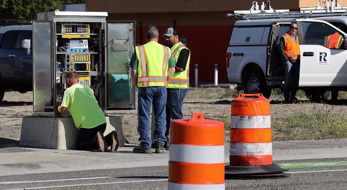 Workers activate the traffic signals for the Wednesday morning opening of the Queensgate Drive extension at Keene Road in south Richland.