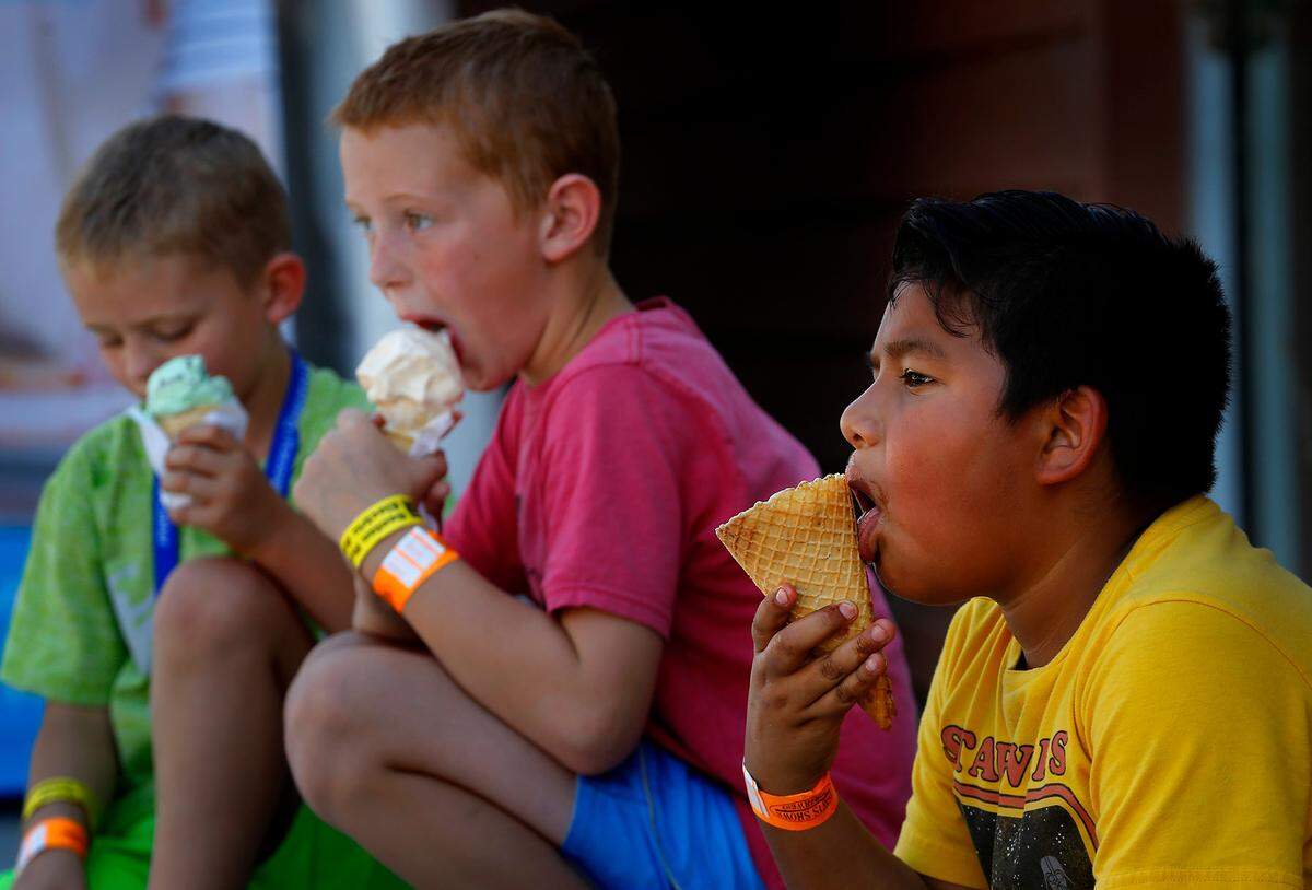 Johan Cruz, right and his two friends Kason Greenfield, left, and Ryan Greenfield sit in a shady spot to enjoy their quickly melting ice cream during their trip to the Benton Franklin Fair and Rodeo in Kennewick. Cruz was there with his mother Laura Noyola of Pasco. Nicole Greenfield of Kennewick accompanied her two nephews.
