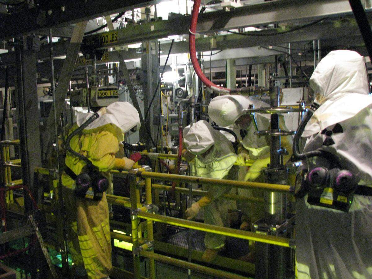 CH2M Hill Plateau Remediation Co. employees work with radioactive waste in a pool beneath the grating they are standing on at a Hanford nuclear reservation K Basin.
