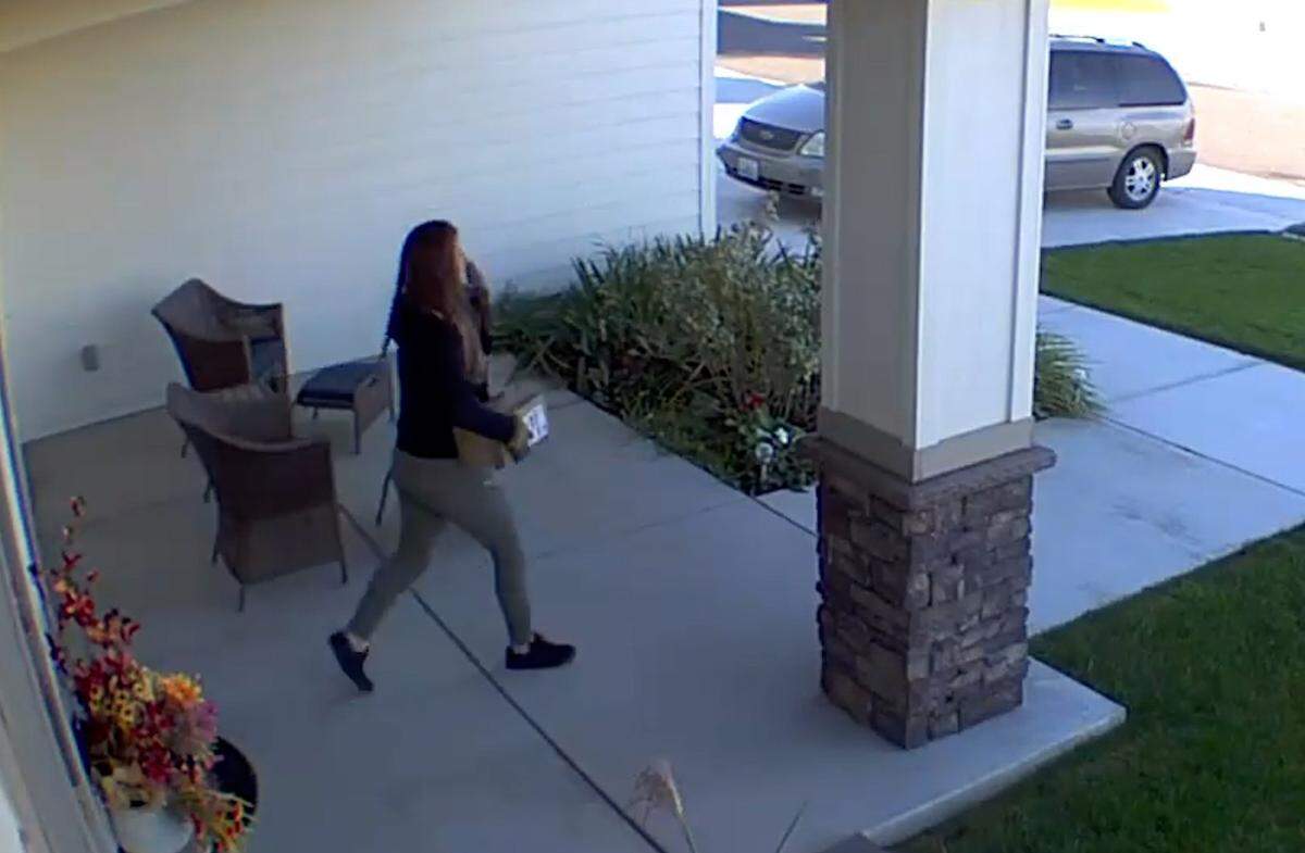 A home security video released by Kennewick Police Department shows a woman taking a package from a front porch in October.