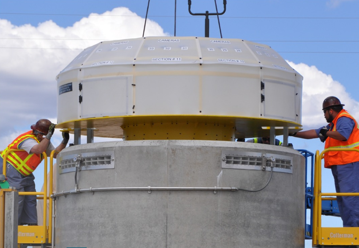 Workers assemble a cask that will be used to store radioactive cesium and strontium capsules on an outdoor pad until they can be permanently disposed.