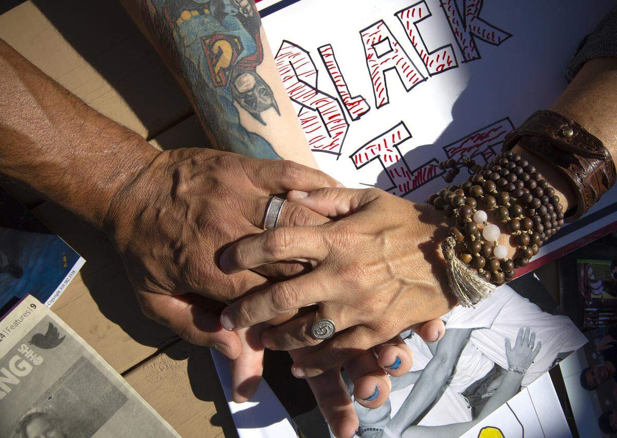 Leo, Tiffany and Darian Slack hold hands. Leo and Tiffany have rings with Gavin’s thumbprint and Darian also has a tattoo honoring his brother on his forearms. It’s a mix of Superman and Batman, because Gavin loved superheroes.  Leo, Tiffany and Darian also have matching tattoos with Gavin’s thumbprint with a white hawk and his name.