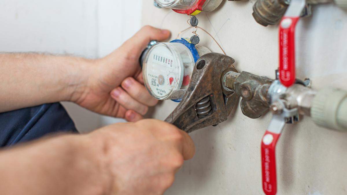 File photo of a plumber fixing water meter with adjustable wrench.