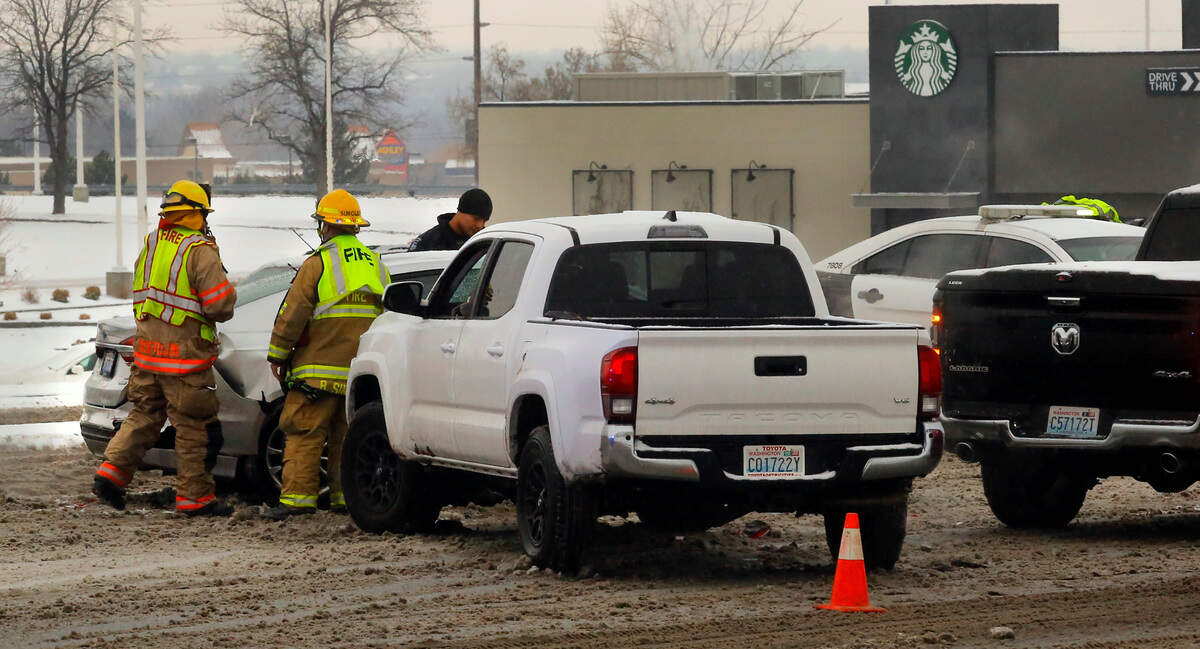 Kennewick firefighters and a Kennewick police officer check on drivers involved in a three vehicle collision Monday afternoon on Columbia Center Boulevard at the intersection with West Canal Drive. Witnesses say the driver of the white Toyota pickup slid into the back of two vehicles, a four-door Ford Sedan and a Ram pickup, that were stopped at the traffic signal in the northbound lanes of Columbia Center Boulevard.