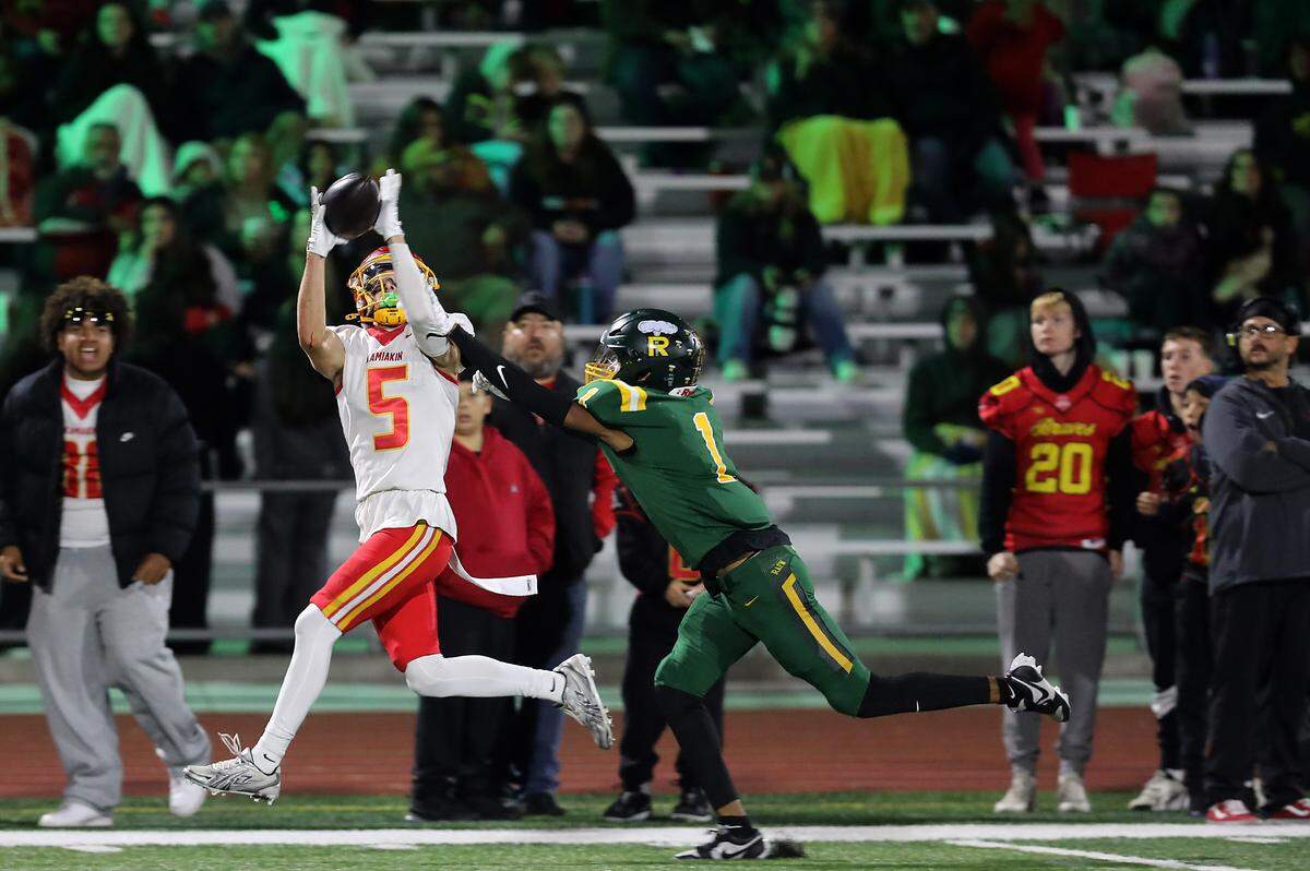 Kamiakin receiver Mason Severson hauls in a pass as Richland defender Kiyen Williams pursues the play during their game in Richland on Oct. 30, 2025. Richland won 15-14 to clinch 2nd seed for the playoffs.