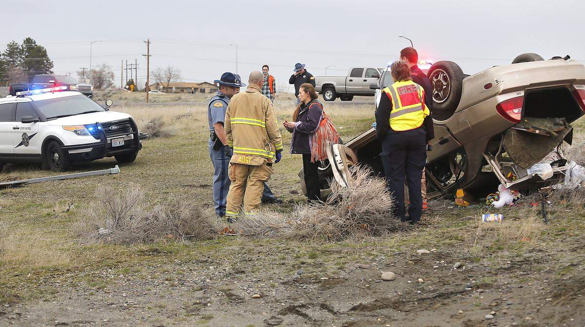 Police and fire officials talk with a woman passenger after Thursday’s rollover wreck near Interstate 182 and Highway 240 in Richland after the driver tried to outrun police.