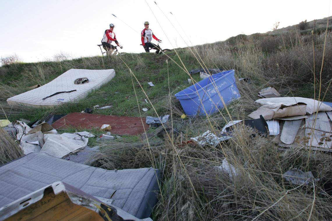 Al Potter and Mike Robinson survey a pile of trash dumped along a private road in the foothills south of Kennewick in this 2012 file photo.