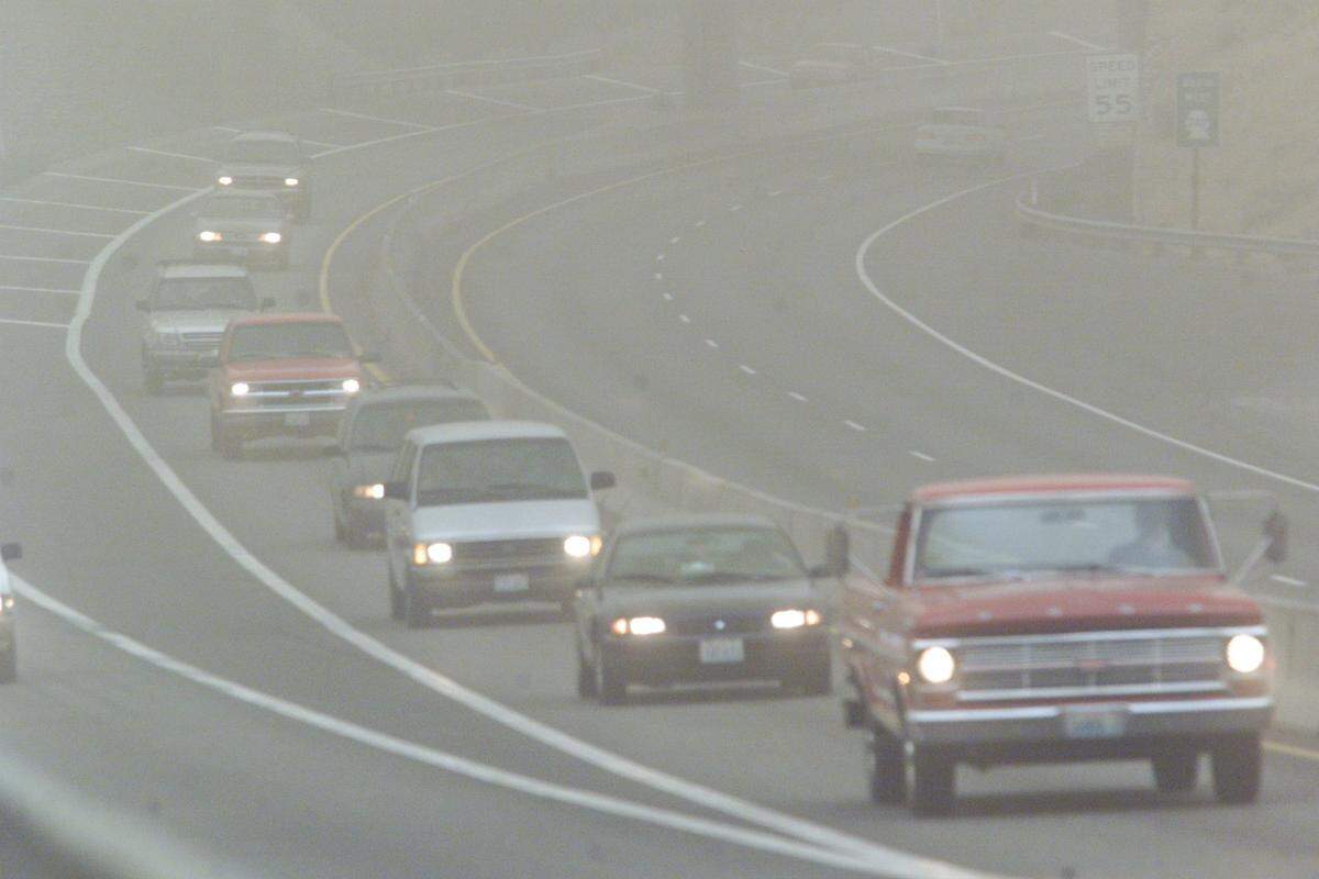 Drivers at the Highway 395 ramp to the blue bridge turn on their lights during a dusty day.