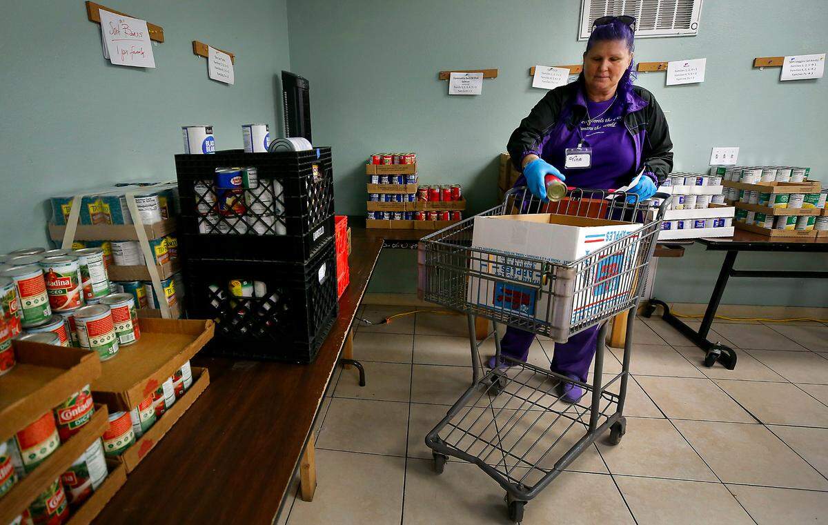 Volunteer Tina Madden fills a cart at the Tri-Cities Food Bank downtown Kennewick at 420 W. Deschutes Ave. with a variety of food items based on a list generated when the client checks in at the facility.