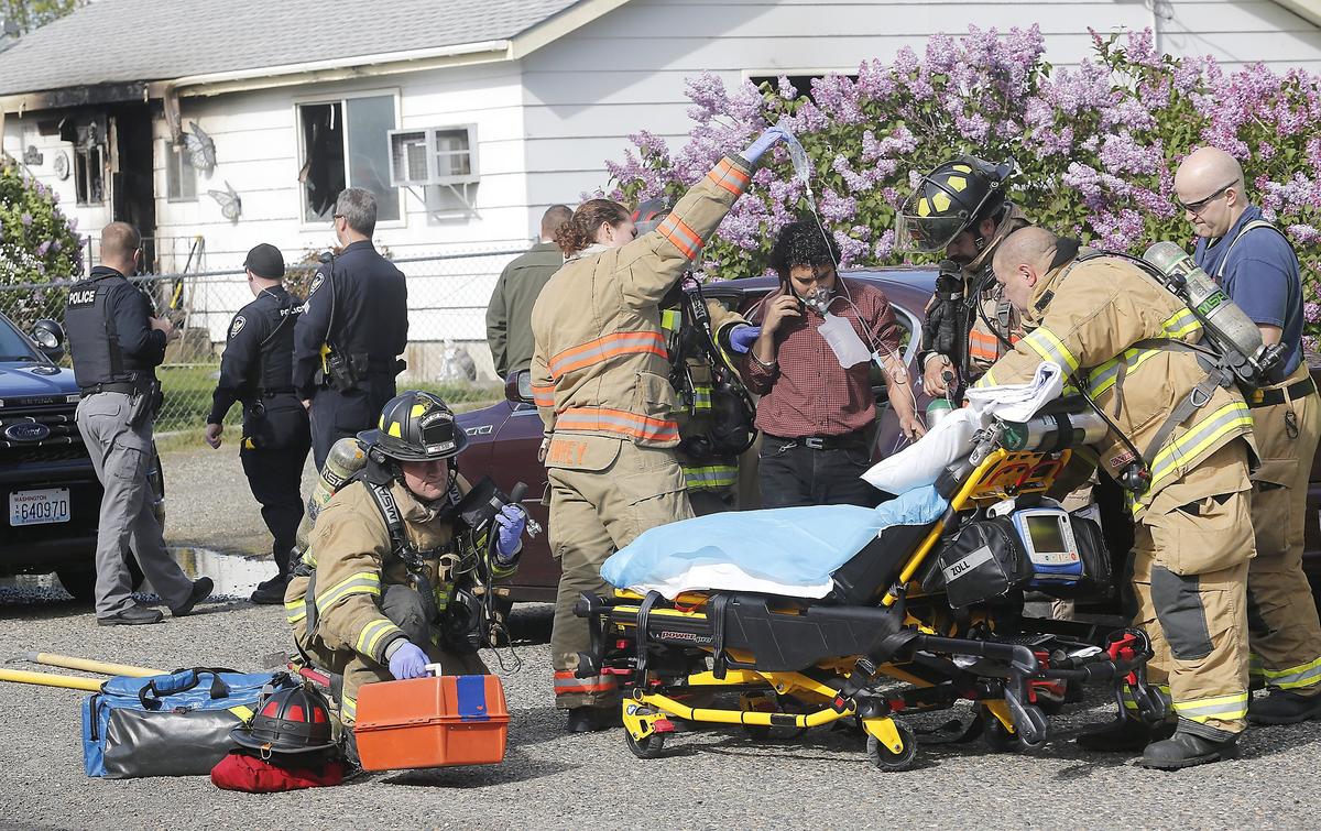 Firefighters and paramedics prepare to take a unidentified male to the hospital that fire officials believe tried rescuing an elderly male trapped inside the burning home in the 1300 block of Dakota Avenue in Richland.