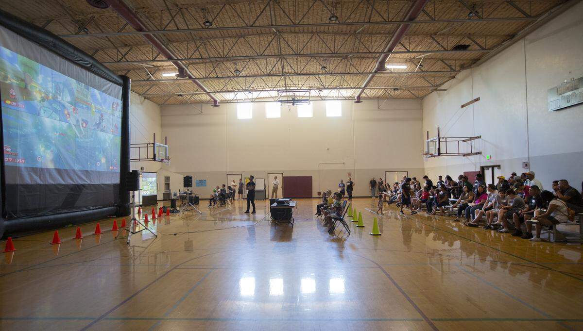 Two big screens were set up inside the gym while each screen had four players competing. Refreshments were available and there were two other television set up with other games to play for people waiting or watching .