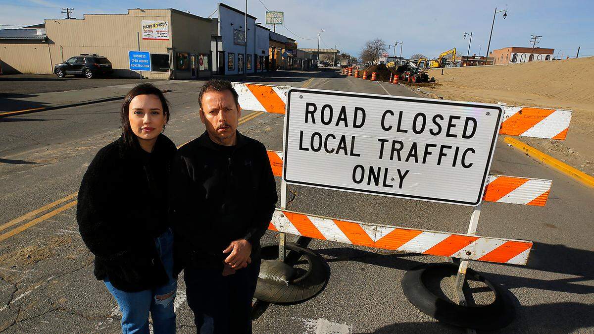 Ramiro Torres, owner of Lewis Street Tires & Torres Auto Repair, stands with his daughter, Valerie Torres, way road barricades for the new overpass project are hurting downtown Pasco businesses.
