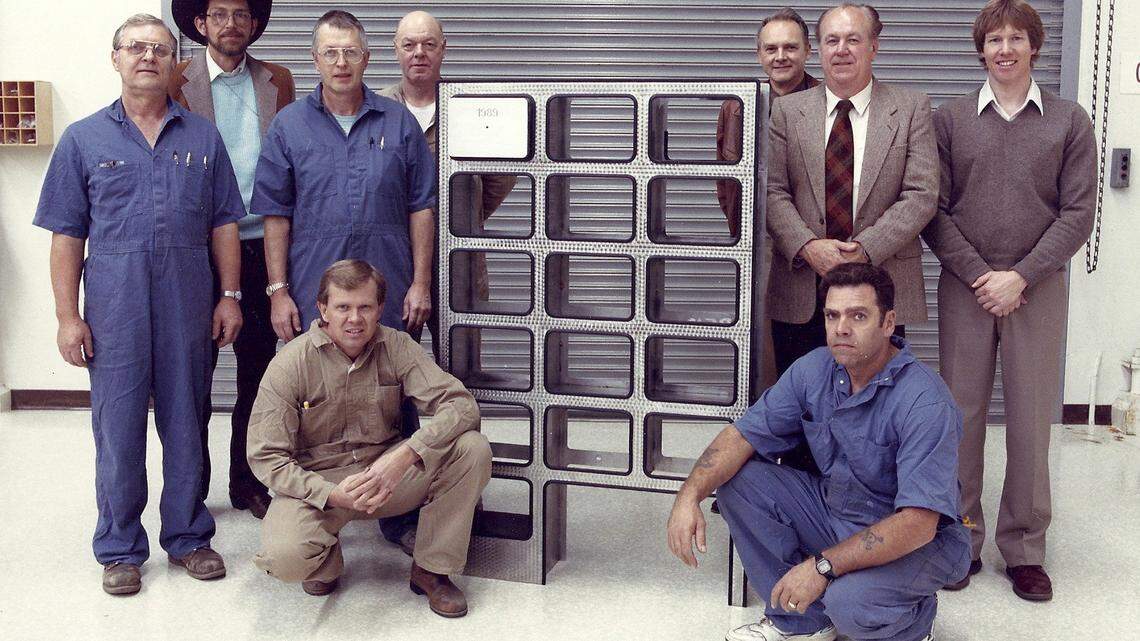 A 1990 photo shows the rack designed and built for the Washington Centennial time capsule. Left to right, standing: Reid Campbell, Carl Scheuerman, Els Collins, Marv Bohling, Dick Hodgson, Jerry Potter, and Jim Homan. Kneeling: Jerry Nelson (left) and George Dvorak.