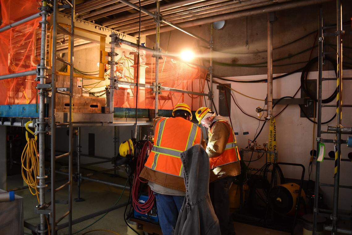 Employees review documents near a pipe rack in the Effluent Management Facility process building at the Hanford vitrification plant.