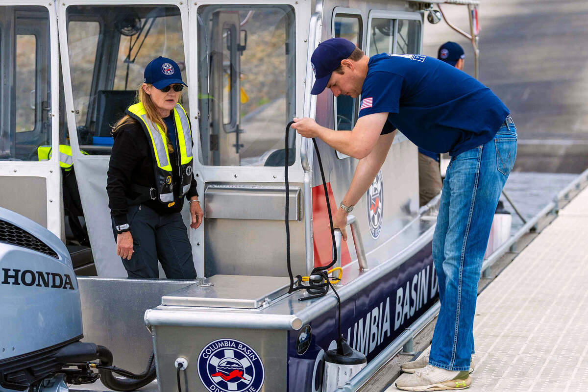 Columbia Basin Dive Rescue boat operator Jessie Bell, left, and diver Ben Prueitt prepare equipment before beginning an evidence search Sunday along the Columbia River near the cable bridge in Pasco.
