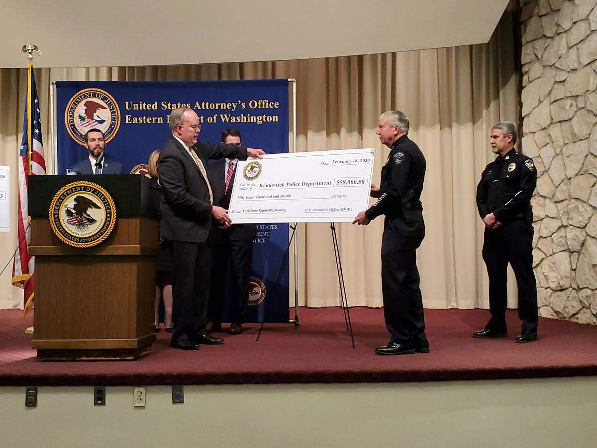 U.S. Attorney William D. Hyslop presented a large, cardboard check for $58,000 to Kennewick Police Chief Ken Hohenberg as part of the federal government’s asset-sharing program. The money was forfeited by a Kennewick man following his conviction for producing child pornography.