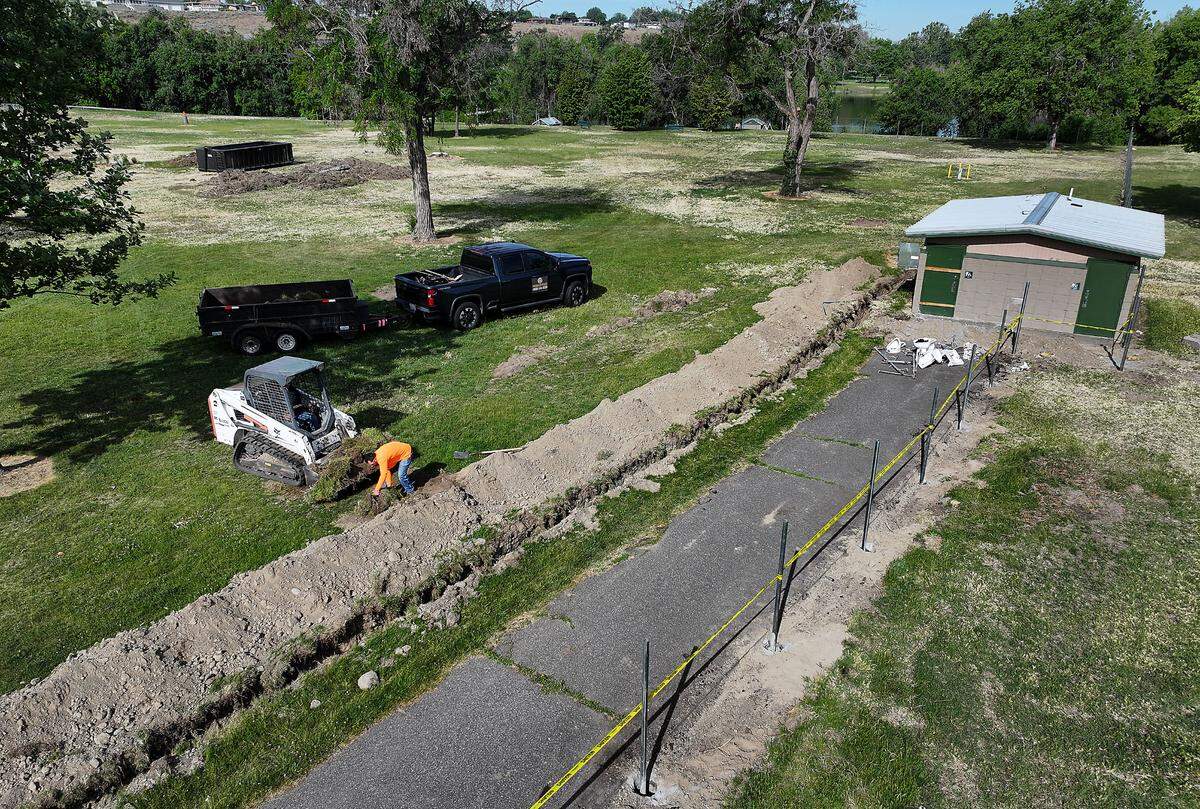 Dan Flud Sr. and Dan Flud Jr. from ProGuard Fence Inc. of Walla Walla remove excess dirt from near the recently installed fence post for the city of Kennewick’s new dog park being constructed in the east end of Columbia Park.