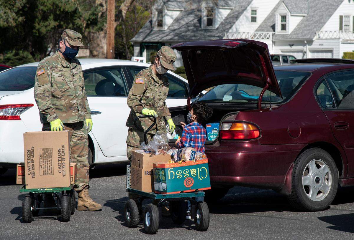 Specialists Dakota Turner, left, and Katelyn Brashear, second from left, of the National Guard help load food into cars on at the Community Services food bank in Pasco, which is sponsored by the Seventh-day Adventist Church.