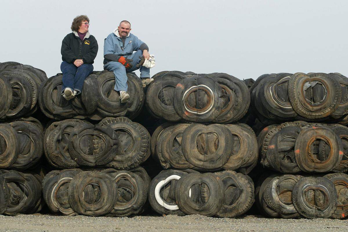 Siblings Sherrey and Mac Hankins sit on tire bales in 2002 at the family business, Northwest Tire Recycling in Richland. The company had hoped to sell the bales for use in shooting ranges, road beds and sound barriers but has struggled to find buyers.