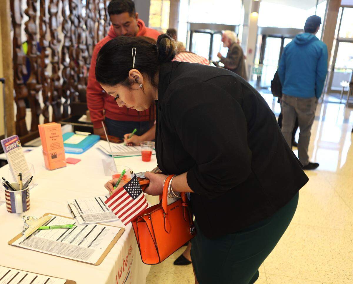 Irma Rodriguez registers to vote after being sworn in as a new U.S. citizen at the U.S. District Court in Richland.