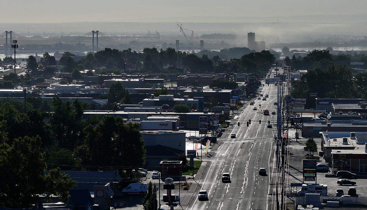 West Clearwater Avenue in Kennewick near North Union Street looking east on a hazy July 29 early morning with cable bridge, Columbia River and Lampson International cranes in the Big Pasco Industrial Area. .