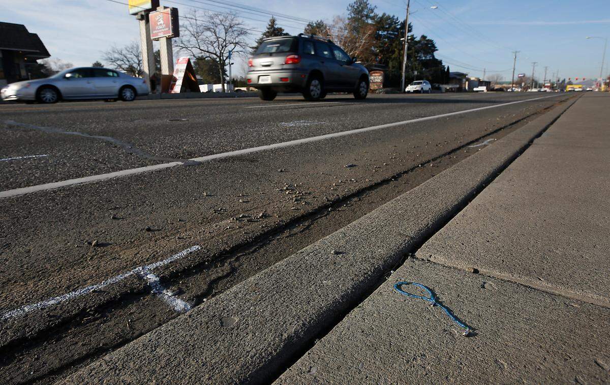 A piece of beaded jewelry sits on the sidewalk near the police investigative paint markings indicate where a 28-year-old woman was hit Sunday night in the middle of Clearwater Avenue in Kennewick. Police are searching for the driver who seriously injured the pedestrian in the westbound lanes in the 5000 block of the five lane roadway.