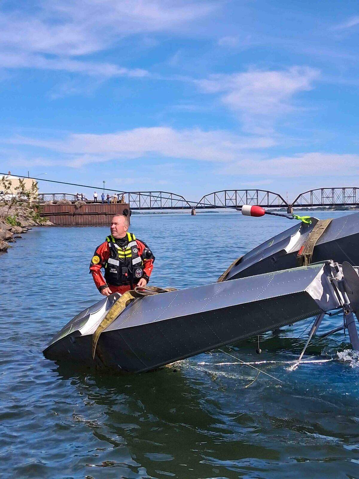 Columbia Basin Dive Rescue crew members work to secure wires to the plane’s floats so it can be lifted out of the river.