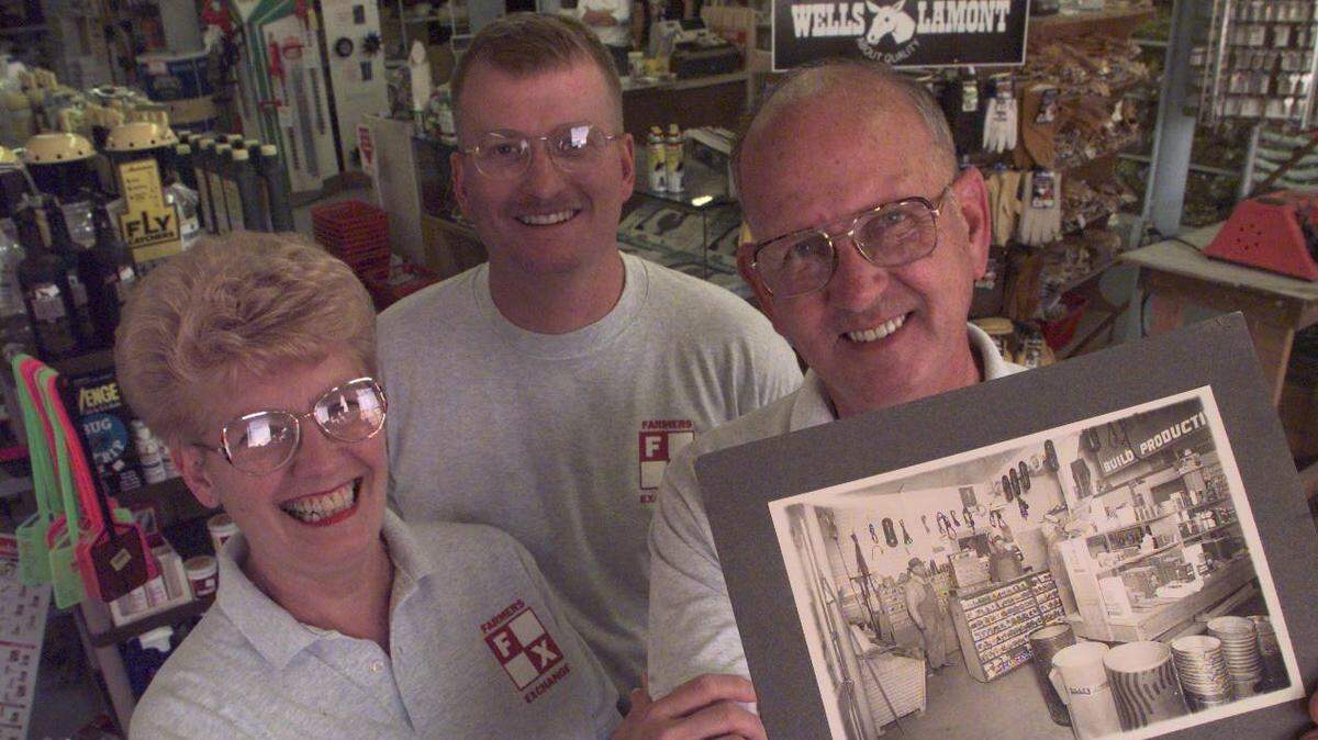 In this 1997 file photo, three generations of the Silliman family have run the Farmers Exchange store on Canal Drive in Kennewick. Ken Silliman, right, received the business from his father, E.A. Silliman, standing at the left in the photograph Ken is holding, which shows the store in 1938 or 1939. Ken and his wife, Arlene, left, signed the store over to their son Keith.