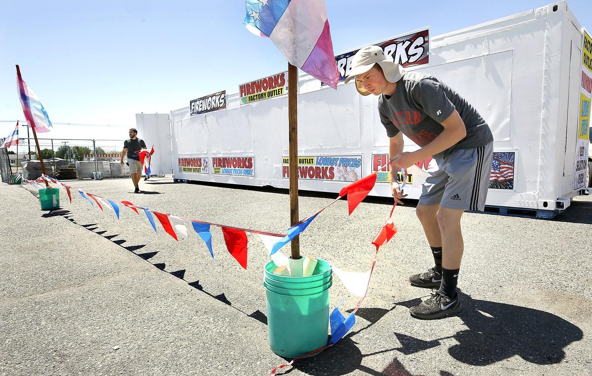 CJ Grigg, left, and Justin Koopman unfurl flagging to mark off the no parking area around the Factory Outlet Fireworks stand Wednesday in the parking lot of the Griggs Department Store in Pasco. Earlier this year, the city council approved the first legal sale and use of fireworks in the city of Pasco in 22 years. The stand will be able to start selling at noon on June 28.