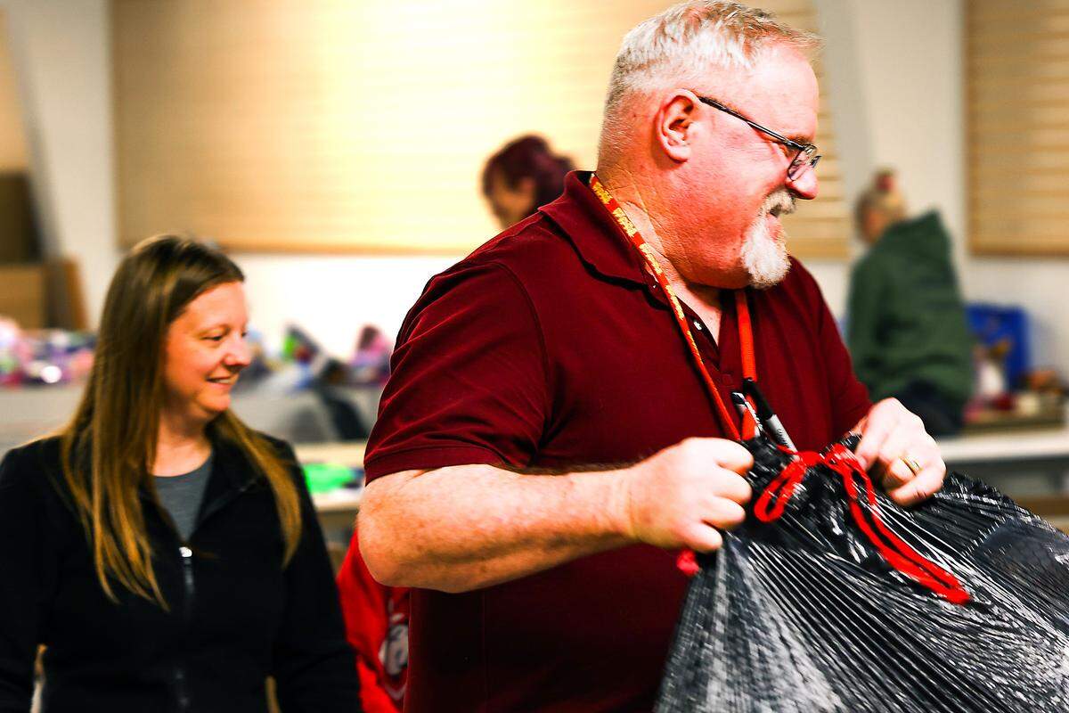 Program coordinator Glen Carter, carries a bag of toys as volunteers help sort, organize, select, and bag up the toys for the families that will get them for Christmas through the Marine Corps Reserve Toys for Tots Santa’s Workshop.