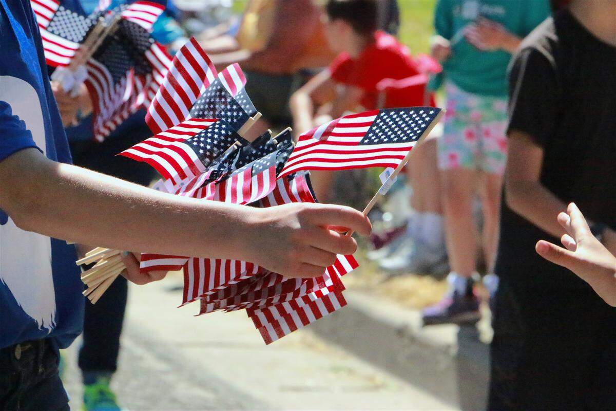 A man passing out American flags along a parade route.
