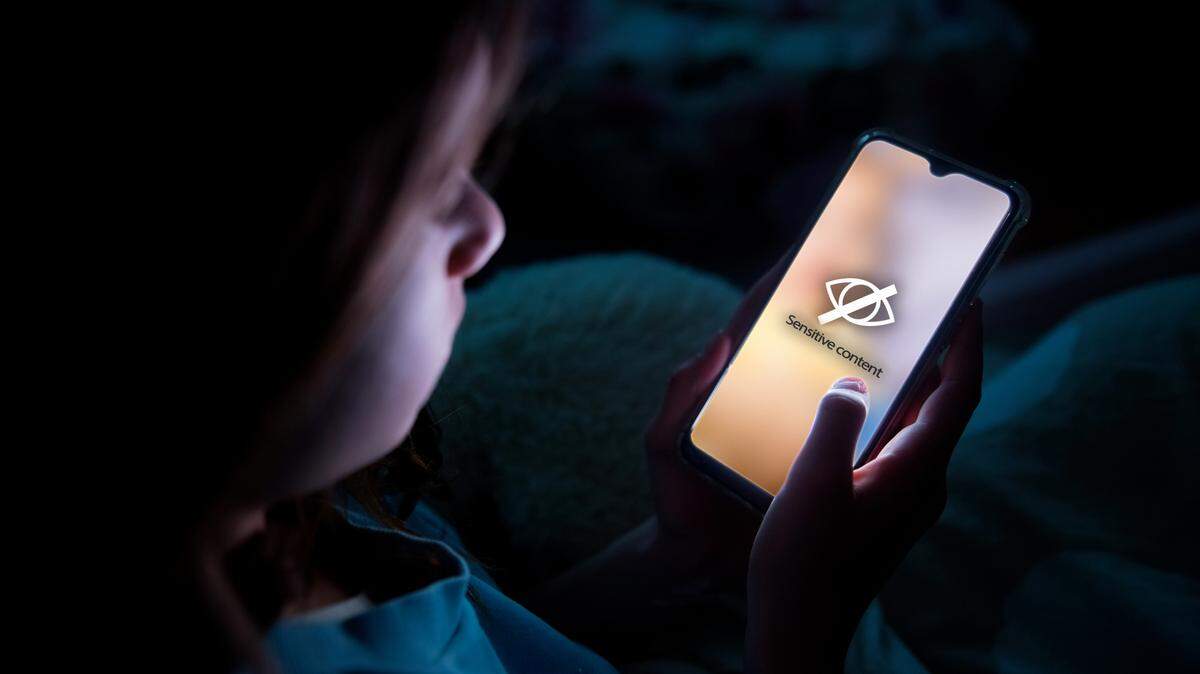 A child using smart phone lying in bed late at night, playing games.