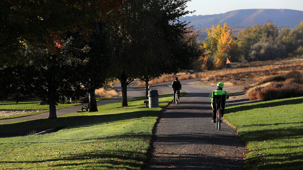 A pair of bicyclists pedal their way down the paved bike path through Leslie Groves Park in north Richland.