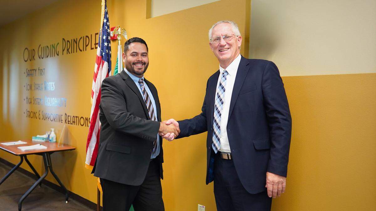 Roger Wright, the Franklin PUD Commission president, shakes hands with Victor Fuentes Tuesday after the commission voted unanimously to name Fuentes the PUD’s general manager and chief executive officer.