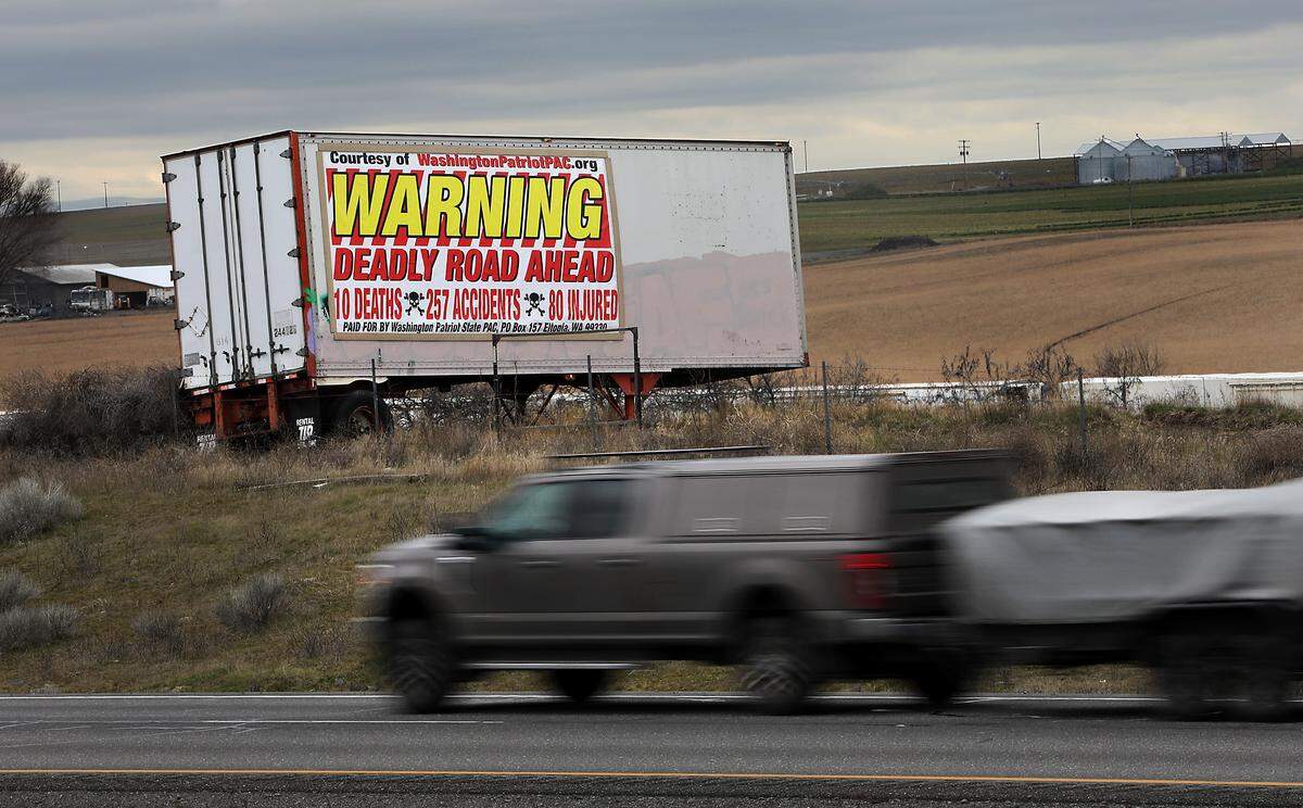 A large billboard attached to a semi-trailer in a field near Sagemoor Road about 16 miles north of Pasco warns southbound drivers of the deadly and dangerous stretch of highway created by cross roads. The banner indicates it has been paid for by Washington Patriotic State PAC in Eltopia.