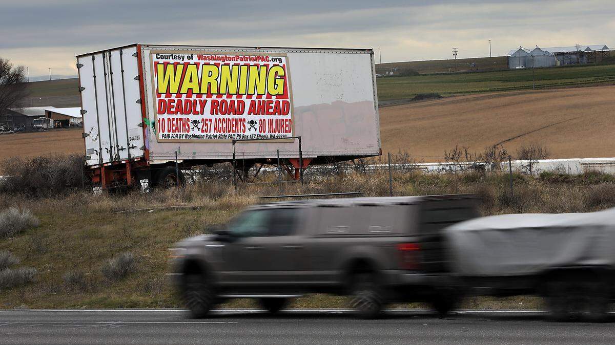 A large billboard attached to a semi-trailer in a field near Sagemoor Road about 16 miles north of Pasco warns southbound drivers of the deadly and dangerous stretch of highway created by cross roads. The banner indicates it has been paid for by Washington Patriotic State PAC in Eltopia.