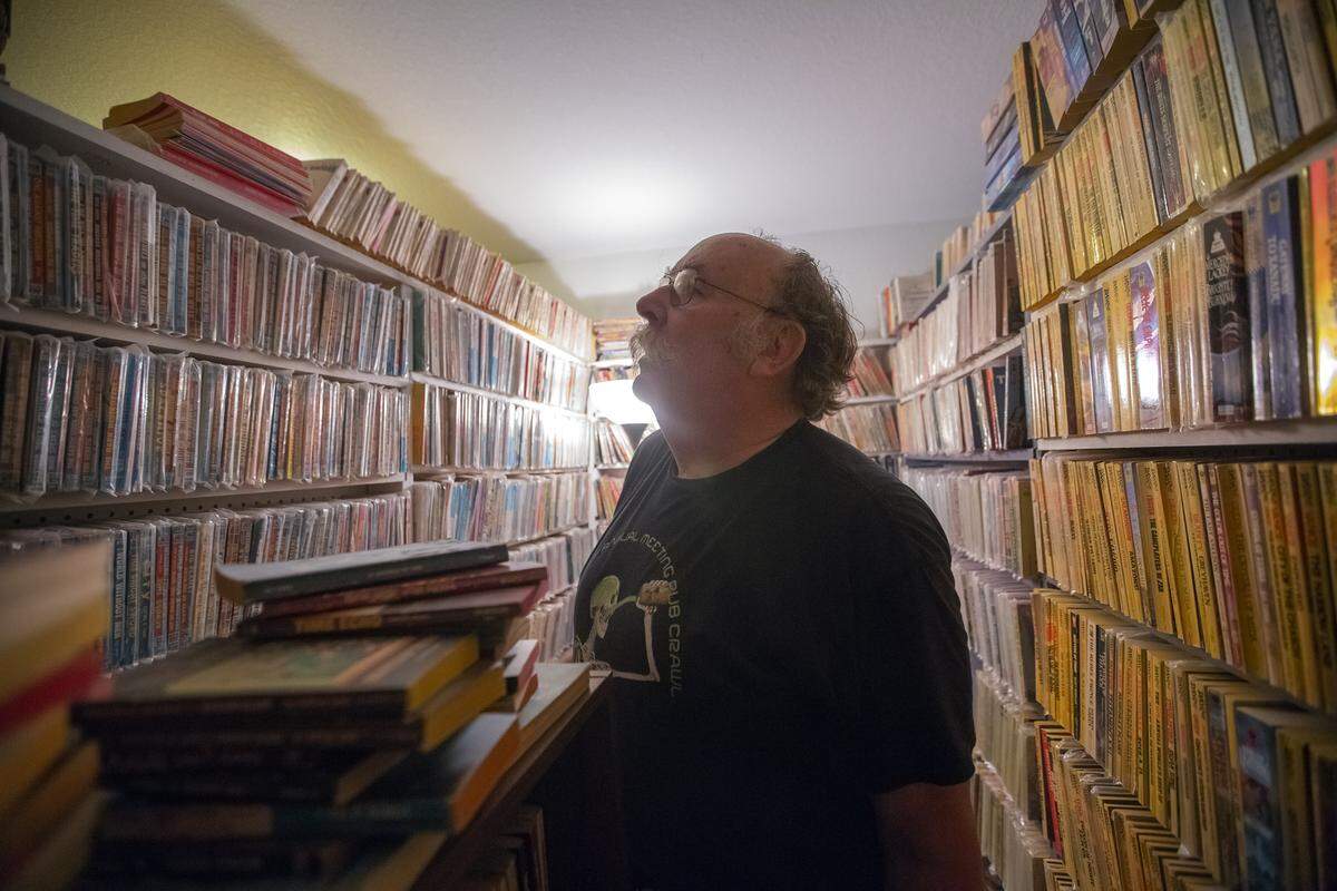 Steven Woolfolk looks at special addition paperback books inside a room of his home in Kennewick. When Woolfolk isn’t reading and buying books, he works at Bechtel as a radiological engineering health supervisor.