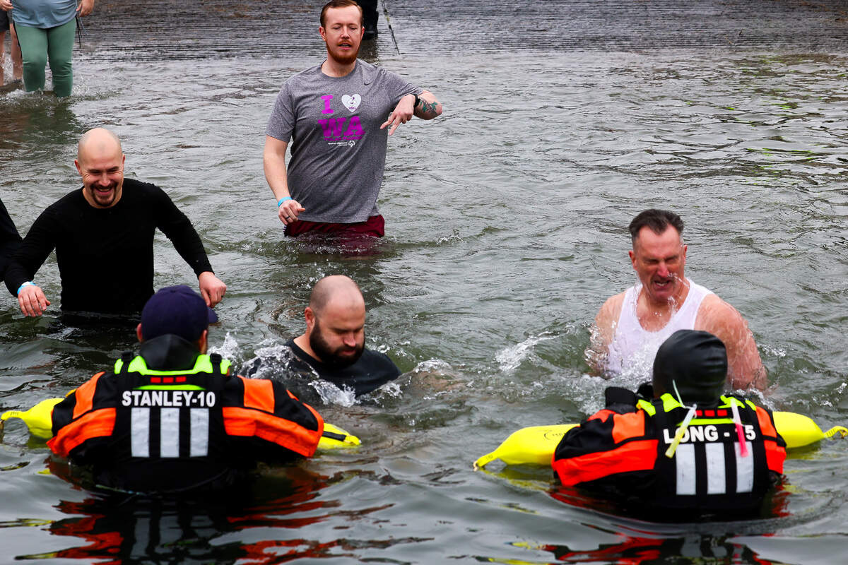 Richland Police Chief Marty Pilcher, right, takes part in the Polar Plunge on Saturday at Columbia Point Marina Park in Richland as members of the Columbia Basin Dive Rescue Squad provide safety support for the event. The annual fundraiser benefits Special Olympics programs in the Tri-Cities.