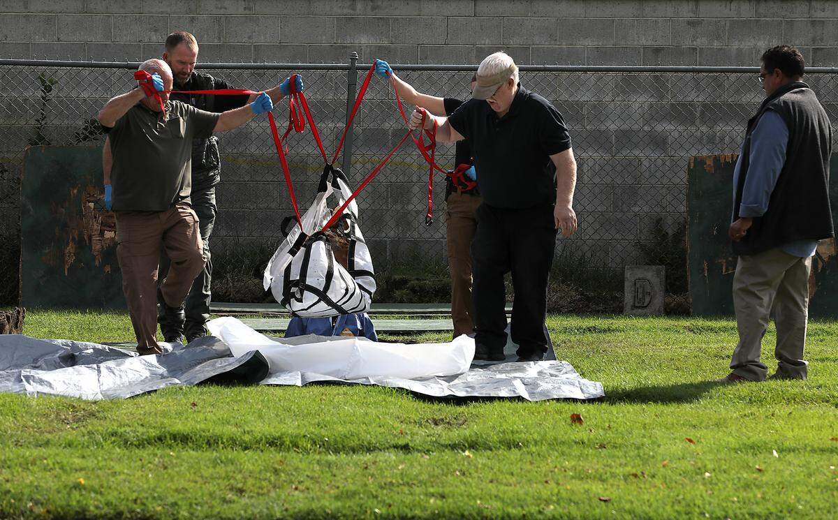 Officials from the Benton County Coroner’s Office and the Benton County Sheriff’s Office lift a box in September 2023 with the remains of an unidentified woman buried at a Richland cemetery nearly 40 years ago.