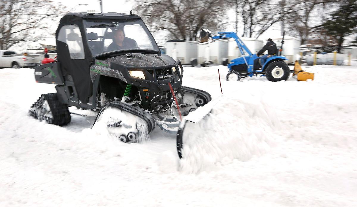Joel Micka, owner of Storage Systems Northwest, powers a track-driven side-by-side UTV outfitted with a snowplow across a parking lot in Kennewick.