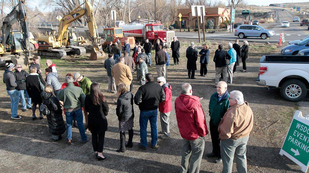 Benton City Mayor Lloyd Carnahan, lower right in green jacket, talks with Claude Oliver, left, and Skip Novakovich, a Port of Kennewick commissioner, following a 2015 groundbreaking ceremony for a new roundabout at the Interstate 82 interchange with highways 224 and 225 in Benton City.