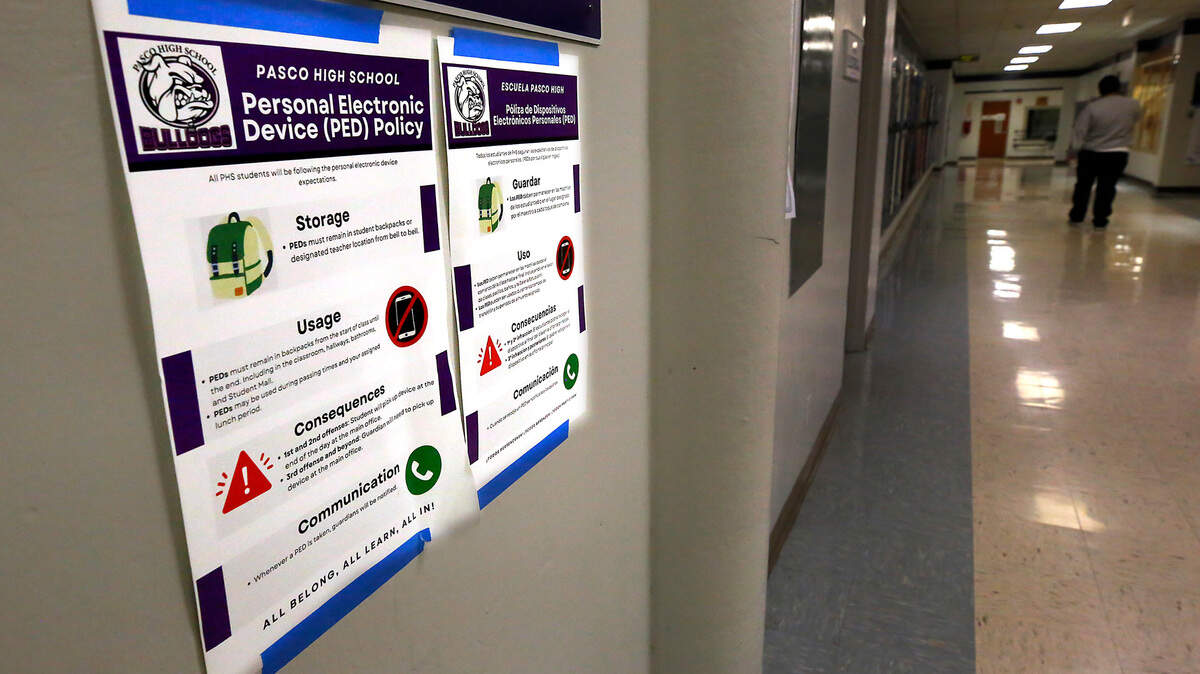 Bilingual posters with the Pasco High School Personal Electronic Device Policy are posted in hallways and classrooms throughout the building.