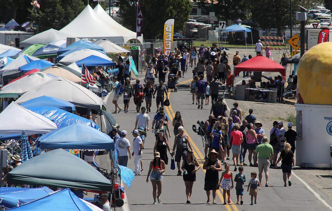 Water Follies fans walk past an ocean of shade canopies lining the Columbia River shoreline in Kennewick's Columbia Park during the annual summer boat racing and air show event.