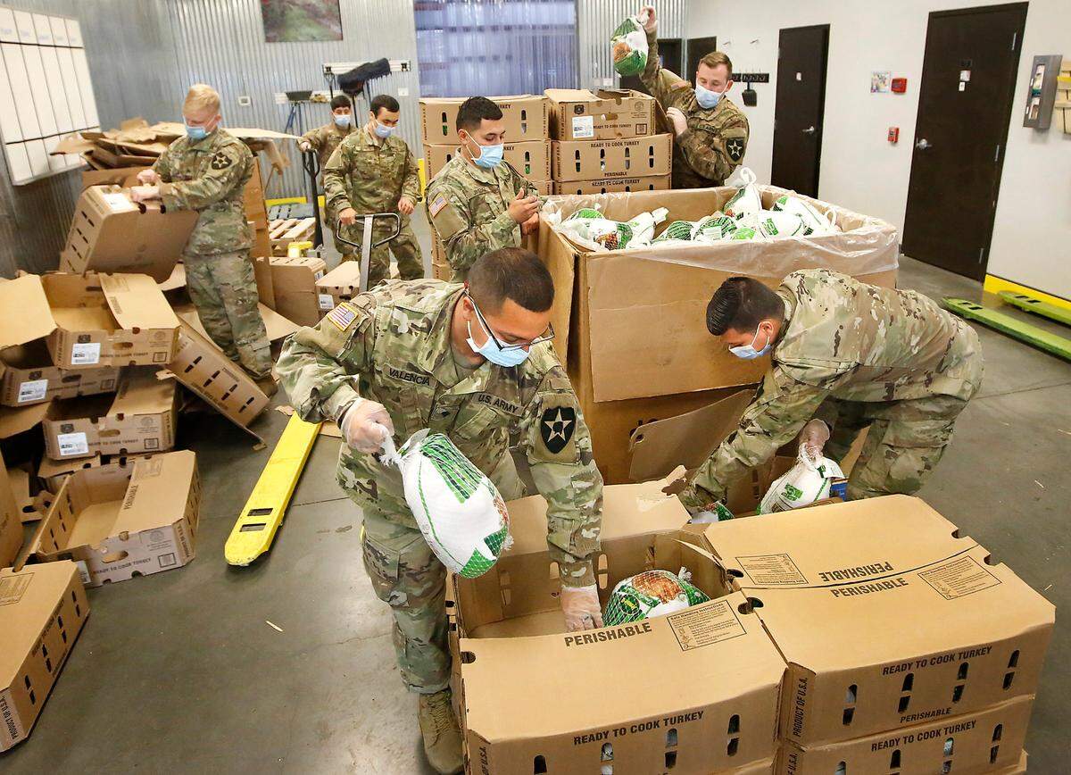 National Guard members transfer cases of individual frozen turkeys to large bins Thursday afternoon at the Second Harvest facility in Pasco in preparation of assembling 2,200 holiday meal boxes for distribution in Yakima, Sunnyside and Kennewick during Thanksgiving week.