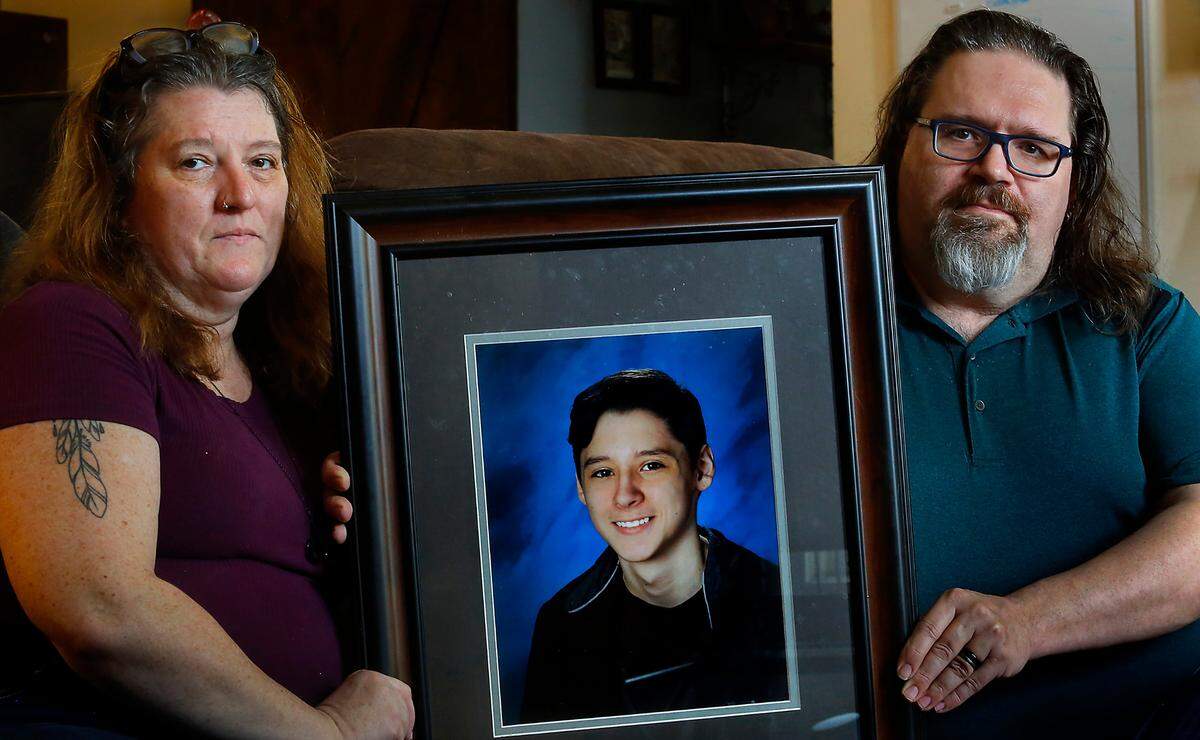 Jim Chastain and his wife, Miriam, hold a portrait of their 17-year-old son, Caelan, a Hanford High School junior who died by suicide in February 2021. They were fighting to have their son recognized at this month’s graduation ceremony.